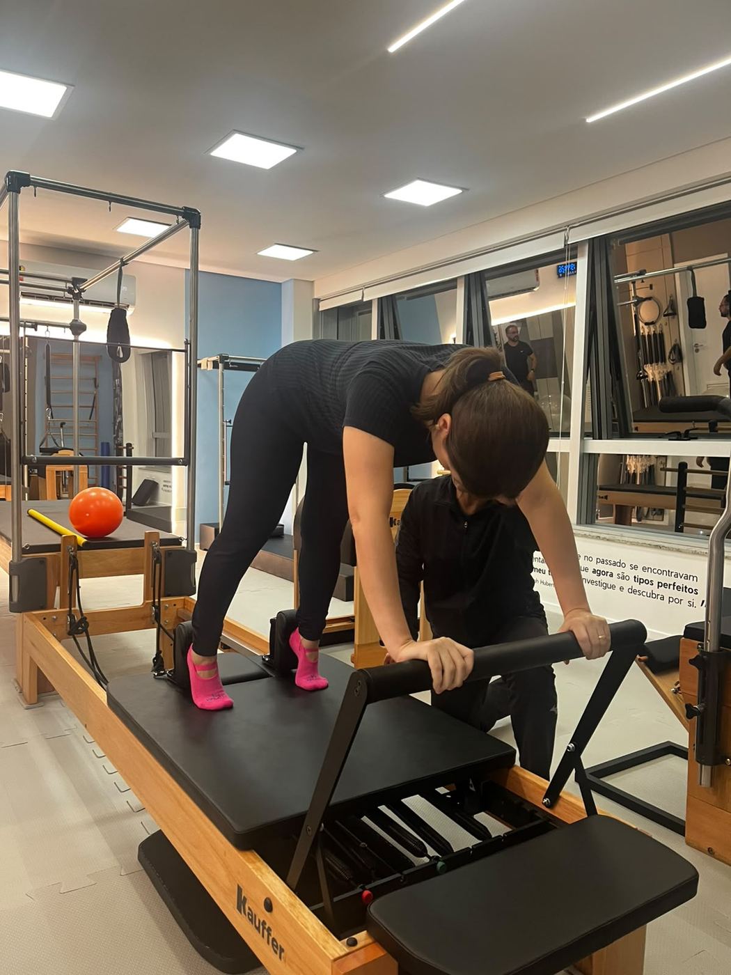 Instrutora auxiliando aluna no Reformer
